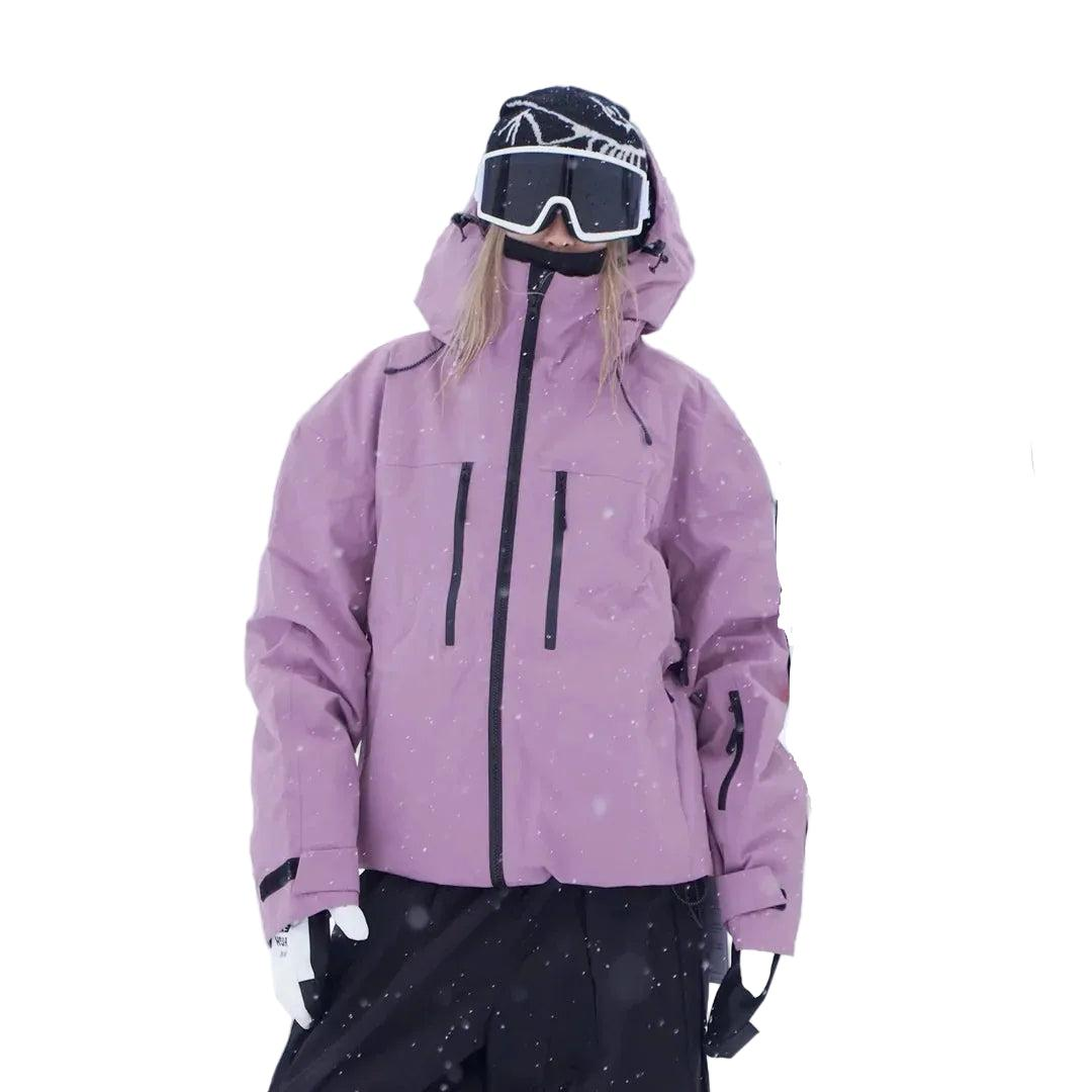 Veste rose mauve portée en pied par un modèle sous la neige, poches zippées de poitrine, manches à sangle et pantalon noir. 4