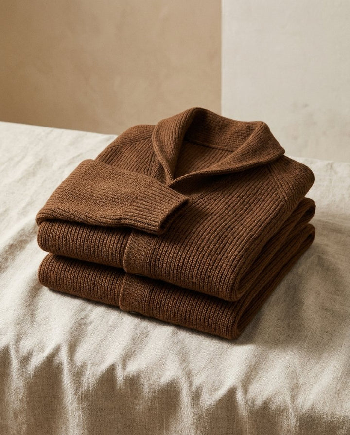 Deux cardigans côtelés marron pliés et empilés sur un tissu de lin clair, col châle et manche repliée visibles. 12