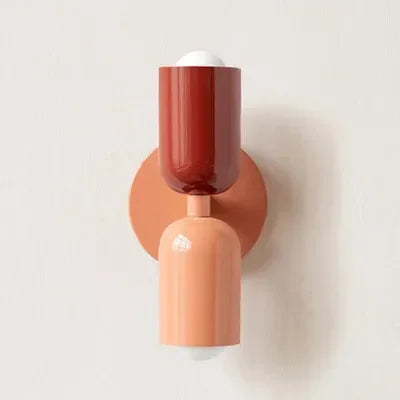 Applique à tête rouge brique et corps corail clair, avec platine corail, vue de face sur mur clair. 20
