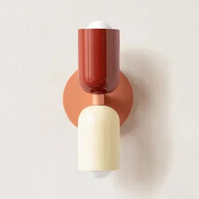 Applique à tête rouge brique et corps crème, avec platine corail, vue de face sur mur clair. 17