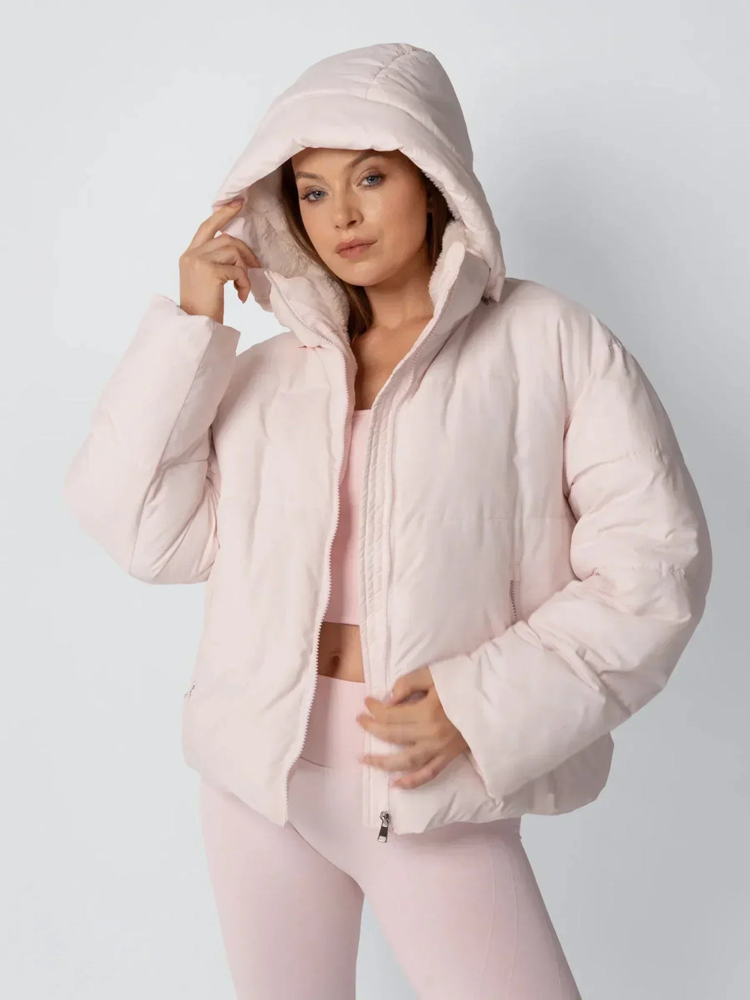 Veste rose pâle portée capuche relevée, une main sur le bord de la capuche 6