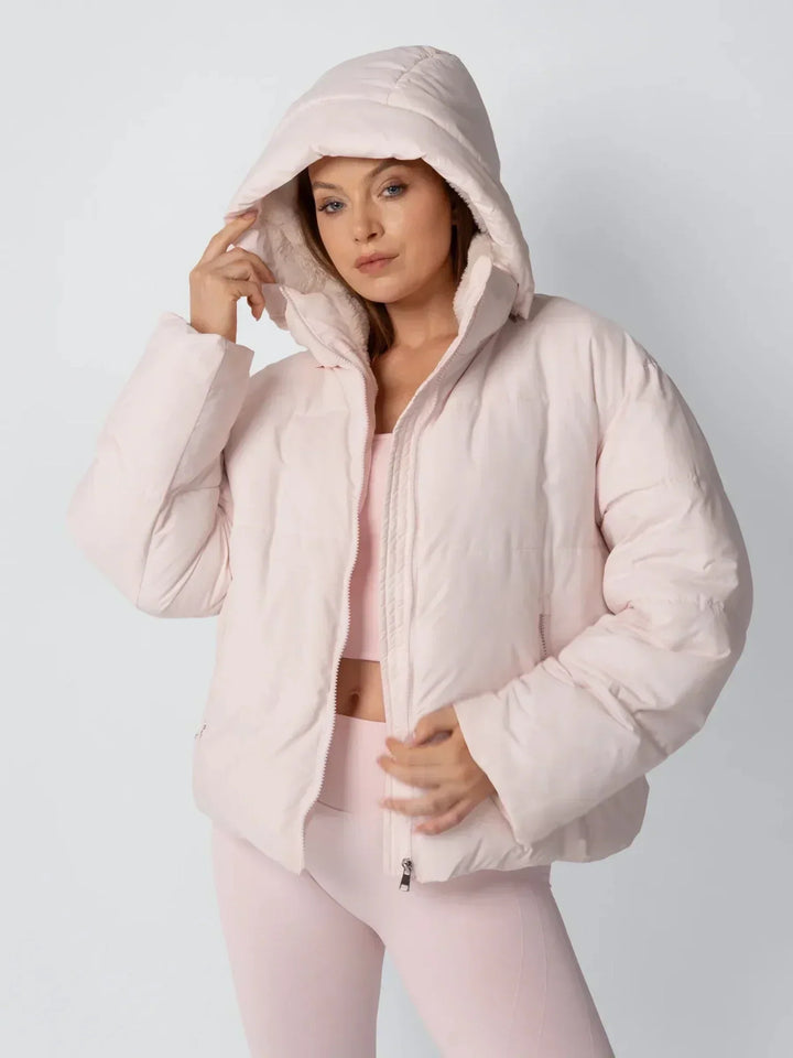 Veste rose pâle portée capuche relevée, une main sur le bord de la capuche 6