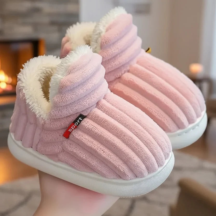 Paire de chaussons roses côtelés à doublure peluche blanche, tenue en main devant un feu de cheminée. 4