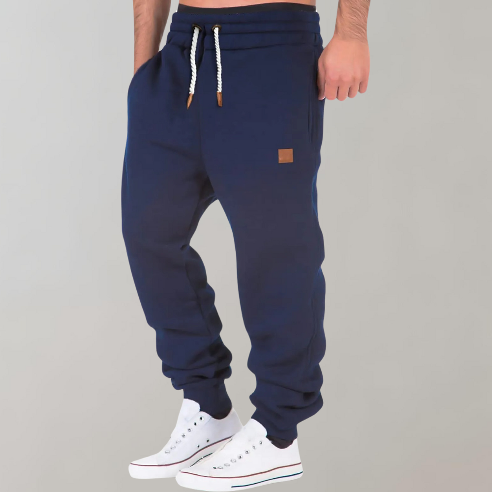 Jogging bleu marine porté par un homme en baskets blanches, vue de trois quarts avec poche 5