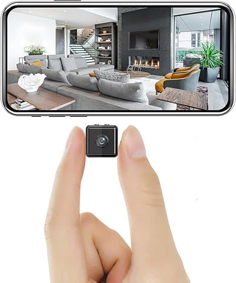 Minuscule caméra cubique noire tenue entre deux doigts, sous un smartphone qui affiche en direct l'image d'un grand salon moderne. 1