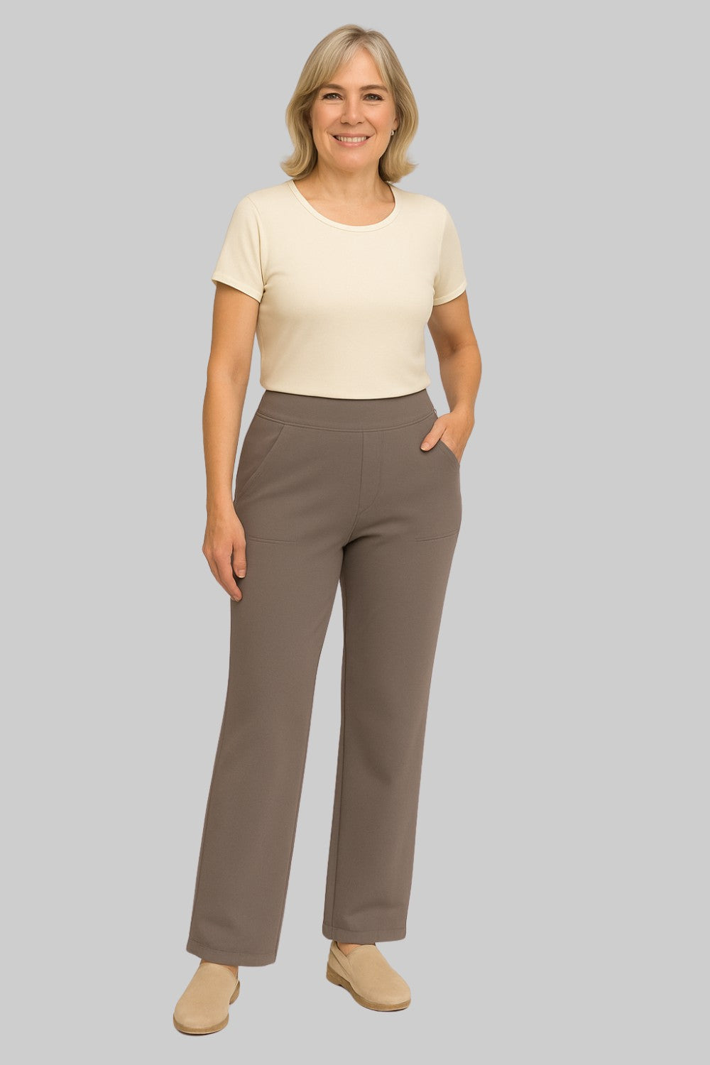 Pantalon taupe porté par une femme souriante avec un t-shirt crème et des mocassins beiges, vue de face en pied. 2