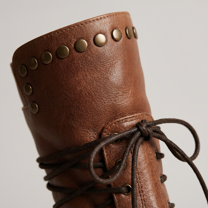 Gros plan sur le haut de tige marron: rangée de rivets métalliques, grain du cuir, couture et lacet noué. 3
