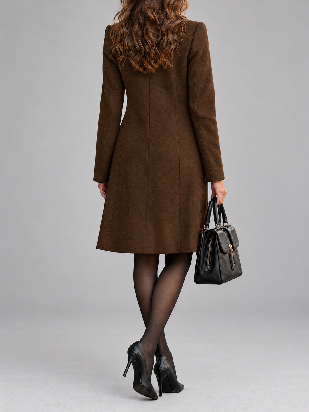 Manteau marron vu de dos, coupe cintrée avec découpes verticales, sac noir à la main 7