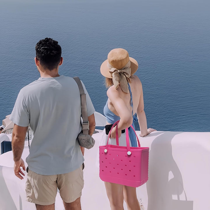 Couple de dos face à la mer, la femme en chapeau de paille tenant un cabas rose vif à la main. 11