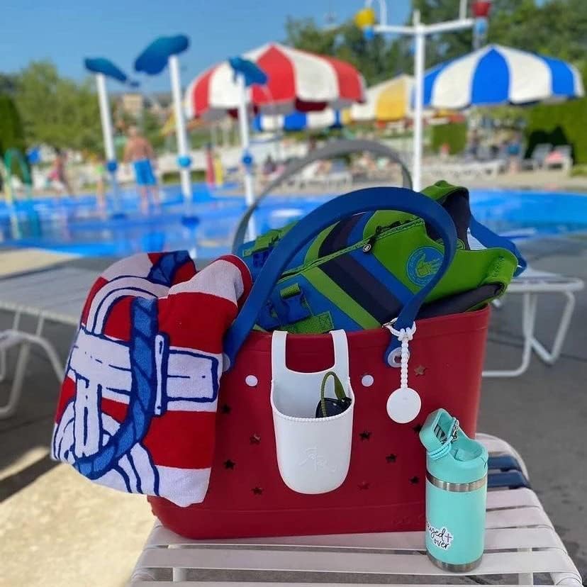 Sac cabas rouge garni d'une serviette rayée et d'un gilet de flottaison, avec poche blanche et gourde, au bord d'une piscine. 24