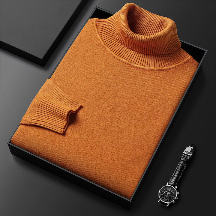 Pull à col roulé orange rouille plié dans une boîte noire, col et manchette côtelés, montre à bracelet cuir à droite. 8