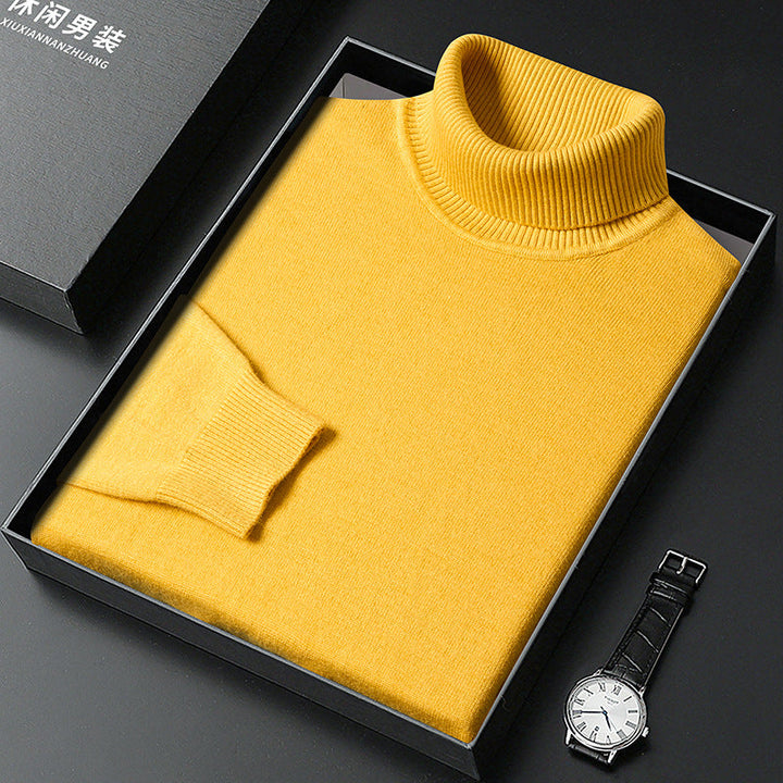 Pull à col roulé jaune plié dans une boîte noire ouverte avec son couvercle, montre à cadran blanc et bracelet cuir à côté. 9