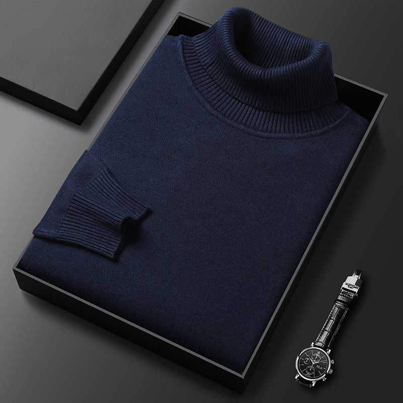 Pull à col roulé bleu marine plié dans une boîte noire, col et manchette côtelés, montre à bracelet cuir à droite. 4