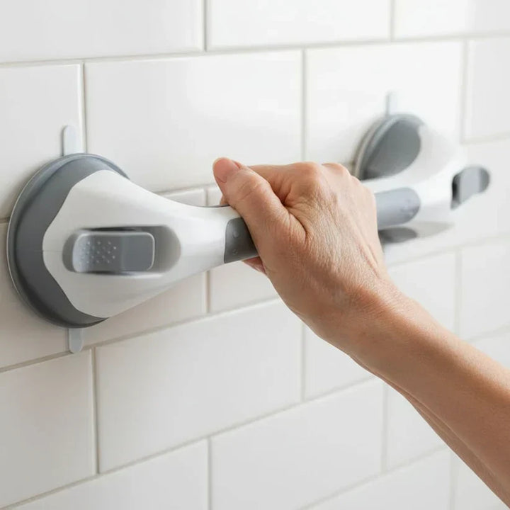 Gros plan d'une main qui saisit la barre blanche et grise fixée par deux ventouses sur un mur carrelé blanc. 2