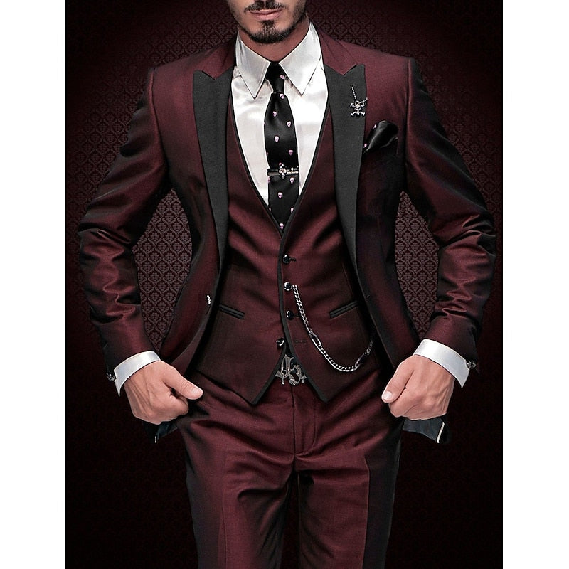 Costume trois pièces bordeaux satiné à revers noirs, porté avec chemise blanche, cravate noire à motifs et chaîne de gilet, sur fond sombre. 5